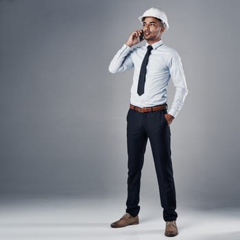 Pushing his team to meet their deadline. a well-dressed civil engineer using his cellphone while standing in the studio