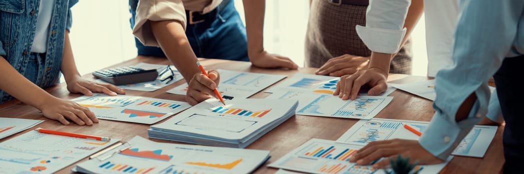 Analyst team utilizing BI Fintech to analyze and pointing at financial dashboard paper office. Businesspeople examining report paper on table for business insight. Panorama shot. Scrutinize