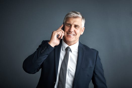 Another big deal coming my way. Studio shot of a mature businessman talking on his cellphone