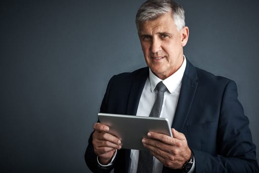 I use it for business and pleasure. Studio shot of a mature businessman using his digital tablet
