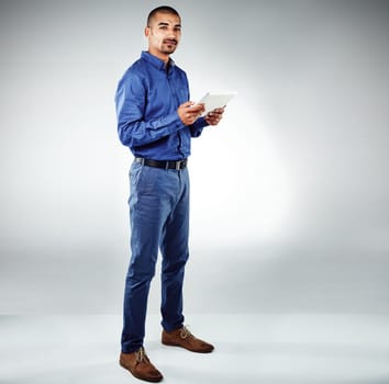 Stay current or ahead of the game. Studio shot of a young businessman using his tablet against a grey background