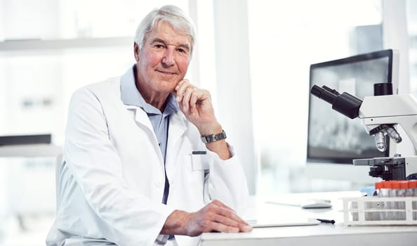 We make the world a safer place. Portrait of a cheerful elderly male scientist making notes while looking into the camera and being seated inside a laboratory