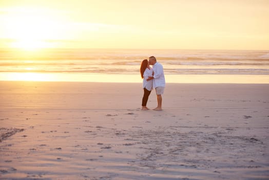 Nothing says romance like a sunset kiss. a mature couple kissing on the beach