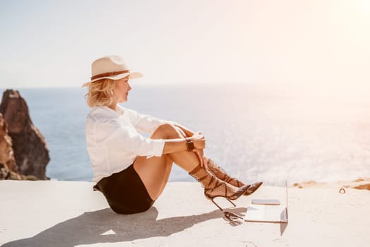 Happy girl doing yoga with laptop working at the beach. beautiful and calm business woman sitting with a laptop in a summer cafe in the lotus position meditating and relaxing. freelance girl remote work beach paradise