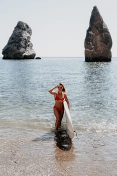 Close up shot of beautiful young caucasian woman with black hair and freckles looking at camera and smiling. Cute woman portrait in a pink bikini posing on a volcanic rock high above the sea