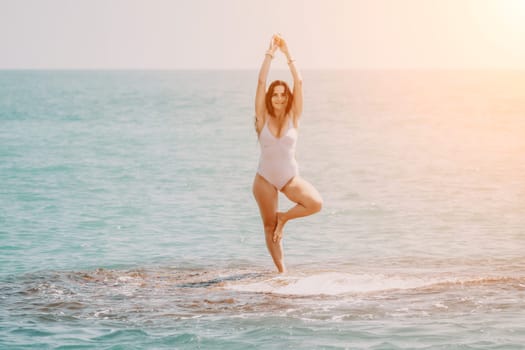 Woman sea yoga. Back view of free calm happy satisfied woman with long hair standing on top rock with yoga position against of sky by the sea. Healthy lifestyle outdoors in nature, fitness concept.