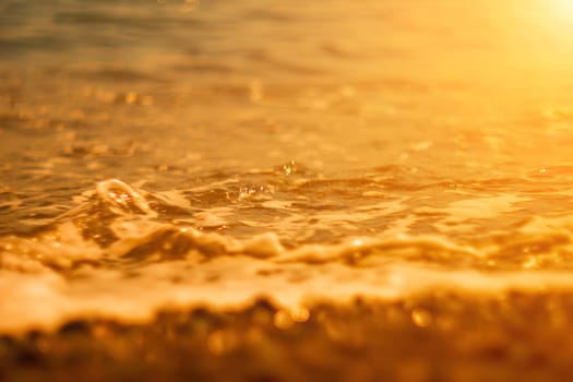 Abstract nature summer or spring ocean sea background. Small waves on water surface in motion blur with bokeh lights from sunrise.