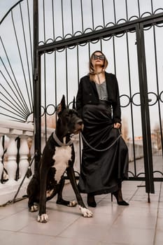 A woman walks with her Great Dane in an urban setting, enjoying the outdoors and the company of her dog