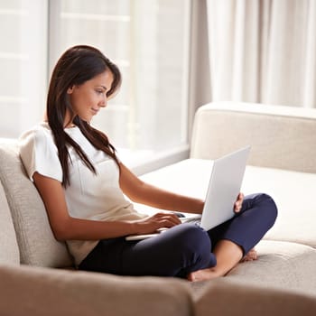 Laptop, typing and a woman with internet on a home sofa for research, remote work or email. Calm female person relax on couch with tech connection for communication or writing social media blog post.
