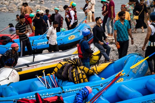 Rishikesh, Haridwar, India - circa 2023: inflatable white water rafts on beach where the adventure sport ends with people taking away rafts and paddles for the next run