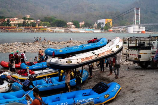 Rishikesh, Haridwar, India - circa 2023: inflatable white water rafts on beach where the adventure sport ends with people taking away rafts and paddles for the next run