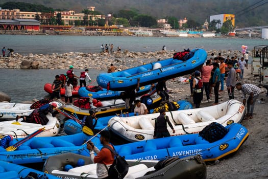 Rishikesh, Haridwar, India - circa 2023: inflatable white water rafts on beach where the adventure sport ends with people taking away rafts and paddles for the next run