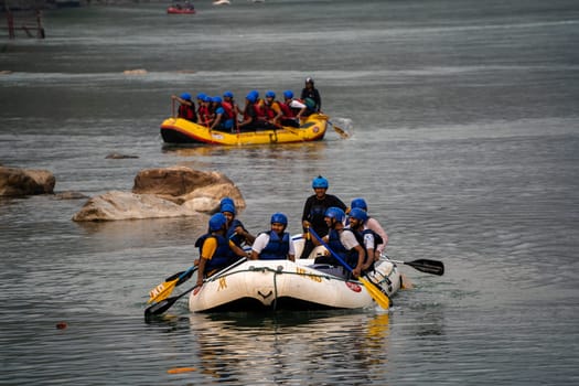 Rishikesh, Haridwar, India - circa 2023: people in helmet jackets rowing raft to shore after white water rafting from shivpuri to rishikesh a popular adventure sport in summers