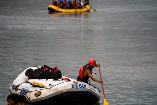 Rishikesh, Haridwar, India - circa 2023: people in helmet jackets rowing raft to shore after white water rafting from shivpuri to rishikesh a popular adventure sport in summers