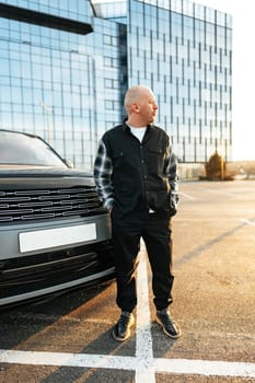 Casual man standing near his luxury car at the parking close up