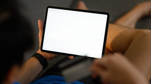 Closeup shot of casual man lying on couch and using digital tablet. White empty screen for advertise text.