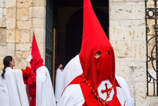 Holy Week in Palencia, Spain. Penitents with red hoods preparing for a procession in the city street.