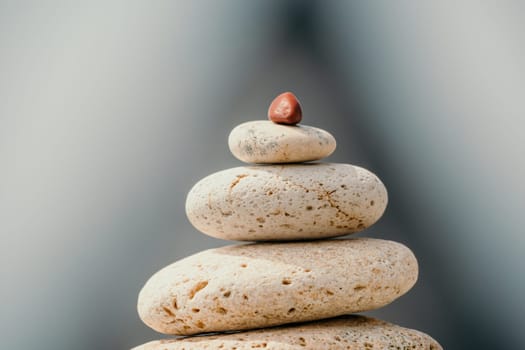 Pyramid stones on the seashore with warm sunset on the sea background. Happy holidays. Pebble beach, calm sea, travel destination. Concept of happy vacation on the sea, meditation, spa, calmness.