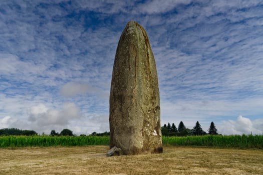 Prehistoric menhir of Champ-Dolent in the French town of Dol-de-Bretagne, without people and with blue sky and light clouds.