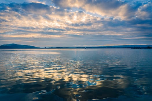 Sunrise landscape of Lake Zugersee in the Swiss town of Zug, calm with blue sky with clouds.