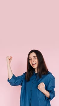 Triumphant Celebration: Photo of an Ecstatic Lady Raising Fists in Joyful Achievement, Embracing Success in an Empty Space, Isolated on a Vibrant Pink Background.