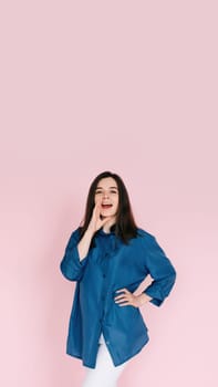 Excited Girl Sharing Breaking News: Hand Near Open Mouth Conveying Surprise and Delivering Important Information in an Empty Space, Isolated on a Pink Background.