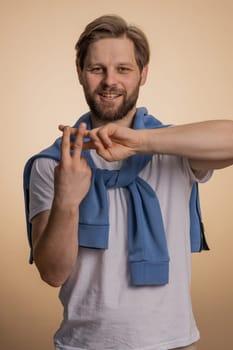 Cheerful caucasian man showing hashtag symbol with hands, likes tagged message, popular viral content, sign to follow internet online trends. Young bearded guy isolated on beige studio background