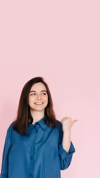 Radiant Portrait of Beautiful Woman with Joyful Smile, Pointing Finger and Looking at Empty Space, Isolated on Pink Background - News and Excitement Concept.