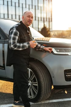 Casual man standing near his luxury car at the parking close up