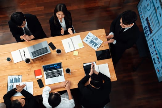 Top view manager or office worker give presentation in harmony conference room to business colleague, BI data dashboard on screen and pile of financial analyzed data reports on meeting table.