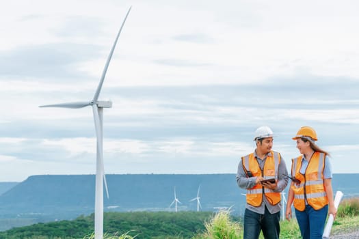 Male and female engineers working on a wind farm atop a hill or mountain in the rural. Progressive ideal for the future production of renewable, sustainable energy.