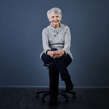 Age is just a number. Studio shot of a cheerful elderly woman sitting with her legs crossed while looking at the camera