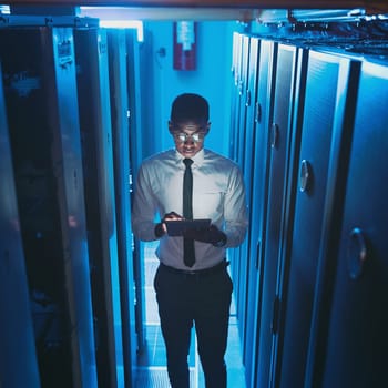 I can code in my sleep. a young IT specialist standing alone in the server room and using a digital tablet