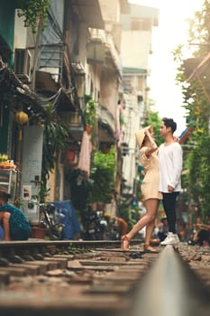 Romance is for every season. a young couple sharing a romantic moment on the train tracks in the streets of Vietnam