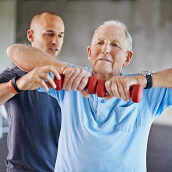 Physiotherapist man, senior patient and weight training for health and wellness therapy in retirement. Healthcare, physio and workout for recovery with a dumbbell for medical care and elderly person.