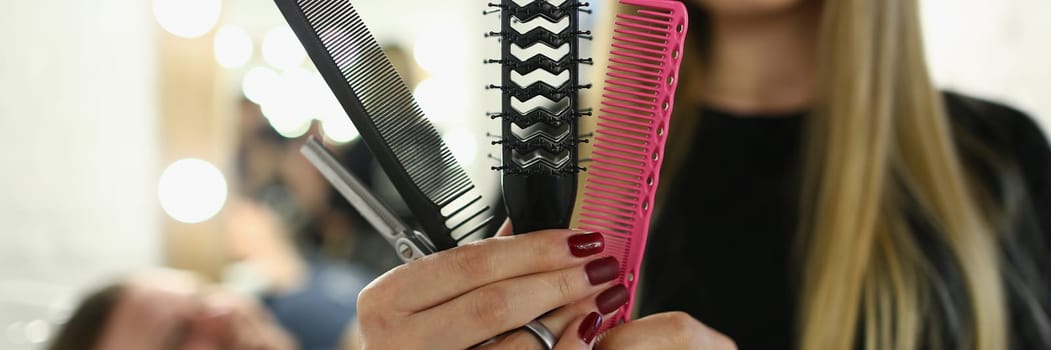Woman hairdresser holding set of combs and scissors in a barbershop. Hairdressing tools concept