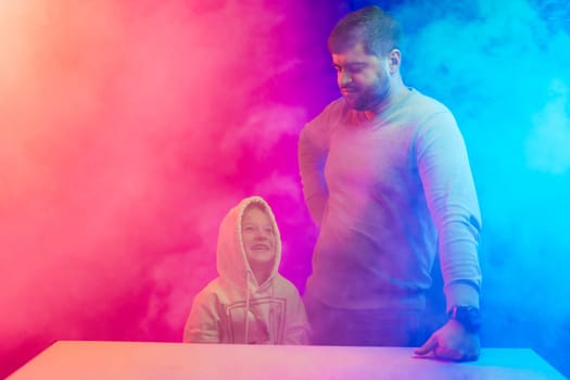 A little girl with her dad stands in the colored smoke in studio