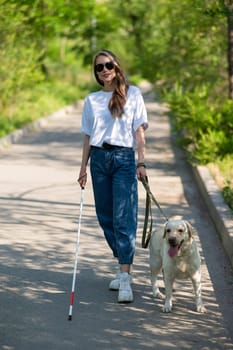 Blind woman walking with guide dog in the park