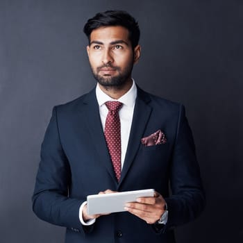 Supporting his decision making with smart technology. Studio shot of a businessman using a digital tablet against a gray background