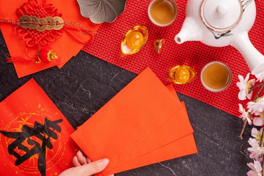 Design concept of Chinese lunar January new year - Woman holding, giving red envelopes (ang pow, hong bao) for lucky money, top view, flat lay, overhead above. The word 'chun' means coming spring.