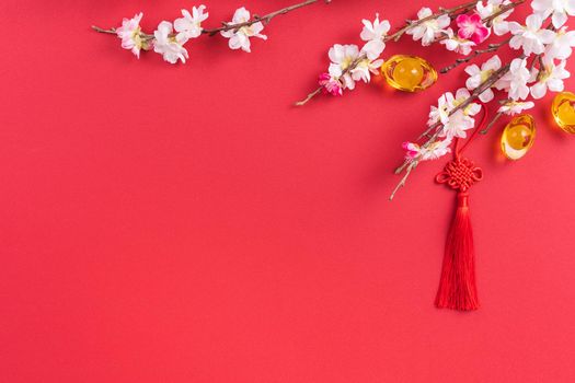 Design concept of Chinese lunar new year - Beautiful Chinese knot with plum blossom isolated on red background, flat lay, top view, overhead layout.