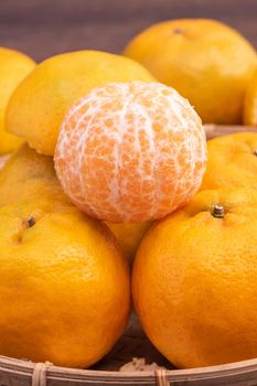 Fresh, beautiful orange color tangerine on bamboo sieve over dark wooden table. Seasonal, traditional fruit of Chinese lunar new year, close up.