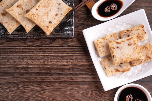 Delicious turnip cake, Chinese traditional radish cake in restaurant with soy sauce for new year's dishes, close up, copy space, top view, flat lay.