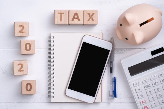 2020 goal, finance plan abstract design concept, wood blocks on white table background with piggy bank, cell phone, top view, flat lay, copy space.