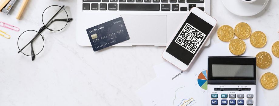 Online payment with QR code concept, virtual credit card, smart phone on office laptop desk on clean marble table background, top view, flat lay