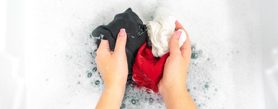 Female hands washing color clothes in basin