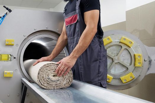 Laundry worker in the process of working on the automatic machine for drying carpets
