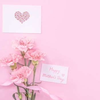 Beautiful, fresh elegant carnation flower bouquet with white greeting thanks gift card isolated on bright pink color background, top view, flat lay concept.