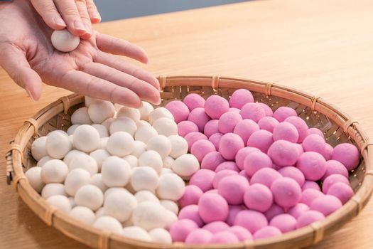 An Asia woman is making Tang yuan, yuan xiao, Chinese traditional food rice dumplings in red and white for lunar new year, winter festival, close up.