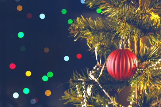 Beautiful Christmas decor concept, bauble hanging on the Christmas tree with sparkling light spot, blurry dark black background, macro detail, close up.